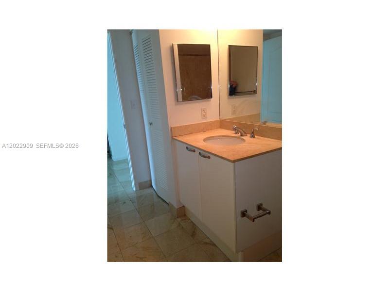 A bathroom features a vanity with a light-colored countertop, a sink, and a wall mirror — 2101 BRICKELL # 410, Miami FL 33131, MIAMI, FL