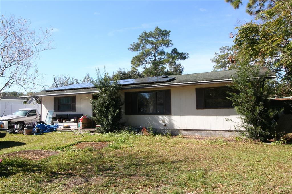 A single-story house with a light-colored exterior, solar panels on the roof, and a yard — 4904 TINKHAM AVENUE, ORLANDO, FL