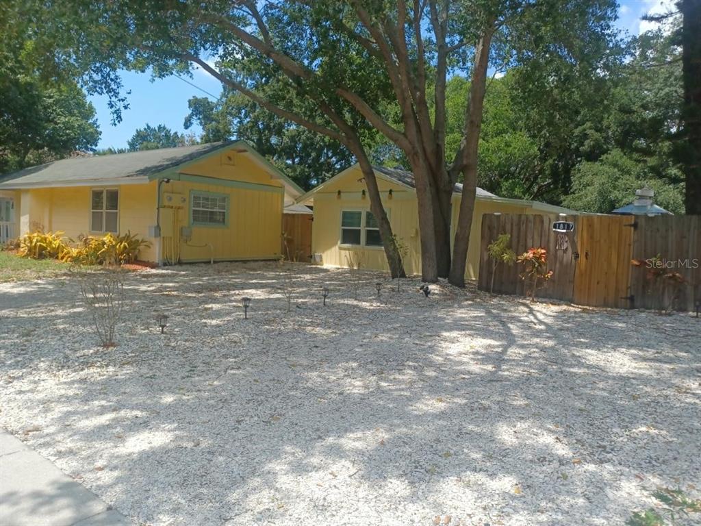 Two yellow houses sit behind a gravel yard with a wooden fence and large trees — 1817 IVANHOE STREET UNIT A&B, SARASOTA, FL