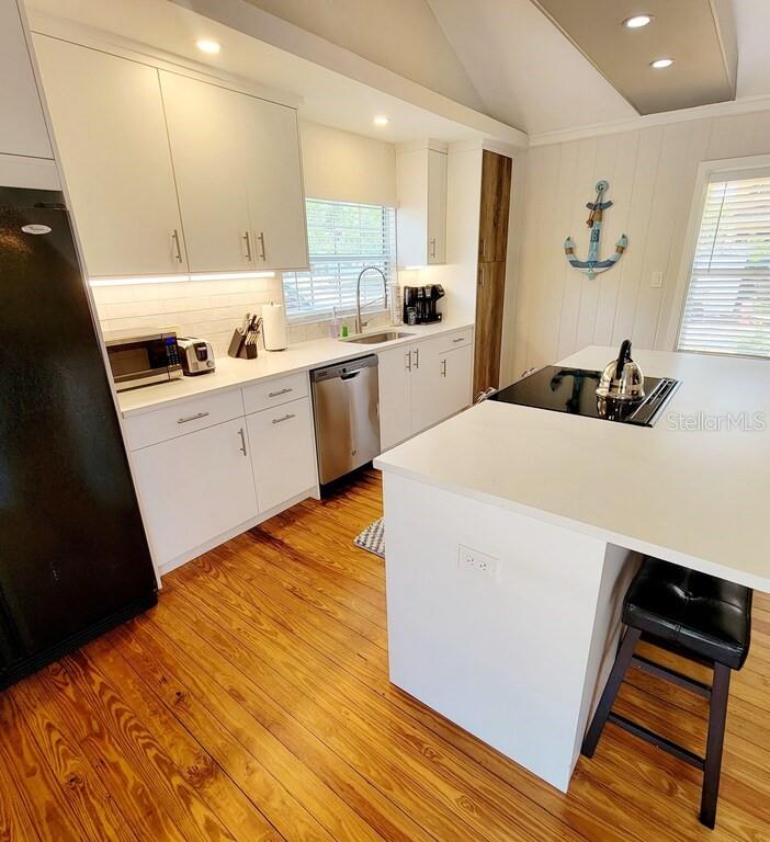 A kitchen features white cabinetry, stainless steel appliances, a center island, and hardwood flooring — 1817 IVANHOE STREET UNIT A&B, SARASOTA, FL