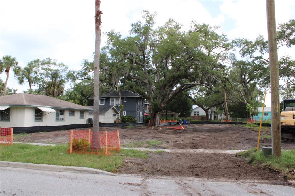 A vacant, grassy residential lot features several large, mature oak trees under a cloudy sky — 308 PRESIDENT STREET, DUNEDIN, FL