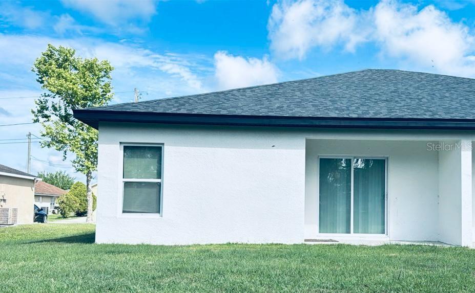 The exterior of a white house features a dark shingled roof and sliding glass doors — 309 CLERMONT DRIVE UNIT B, POINCIANA, FL