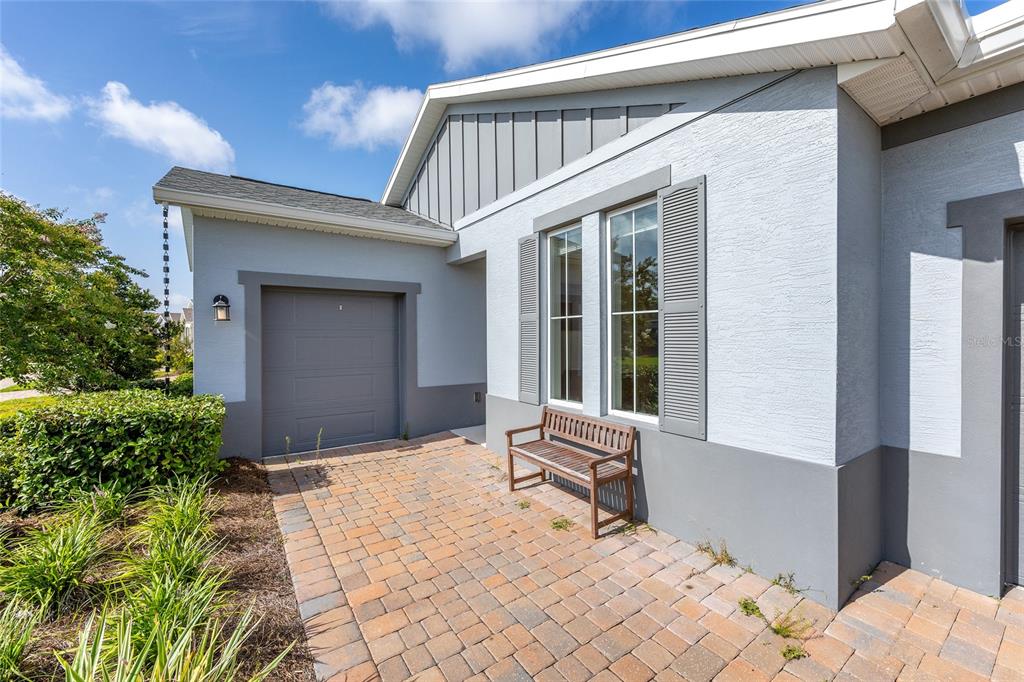A paved patio area sits in front of a gray house with a small garage — 4342 NW 55TH COURT, OCALA, FL