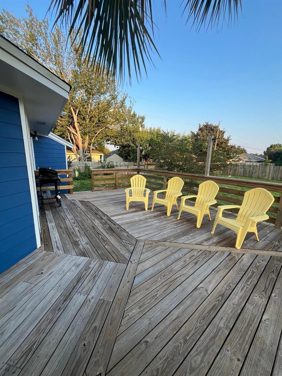 A wooden deck features four yellow Adirondack chairs and a grill beside a blue house — 2040 Falconhurst Place # 2040, FL 32566, FL