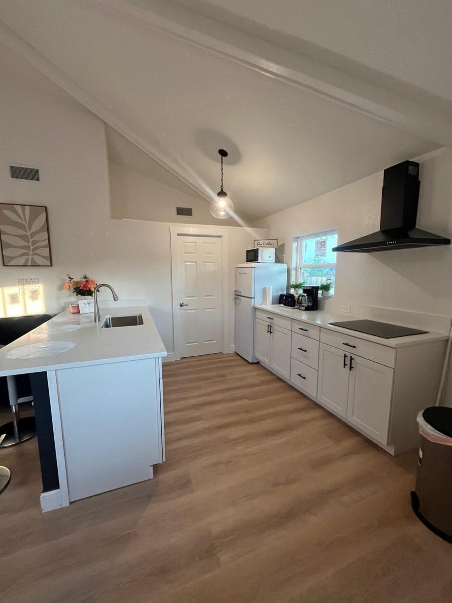 A modern kitchen features white cabinetry, a central island with a sink, and light flooring — 2040 Falconhurst Place # 2040, FL 32566, FL