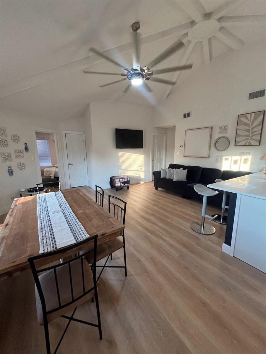 An open-concept living and dining area features vaulted ceilings, wood-look flooring, and a ceiling fan — 2040 Falconhurst Place # 2040, FL 32566, FL