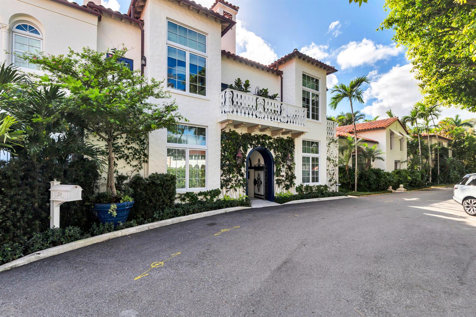 A white Mediterranean-style house with a balcony, arched entryway, and lush landscaping along the street — 236 Phipps Plaza # 201, Palm Beach FL 33480, PALM BEACH, FL