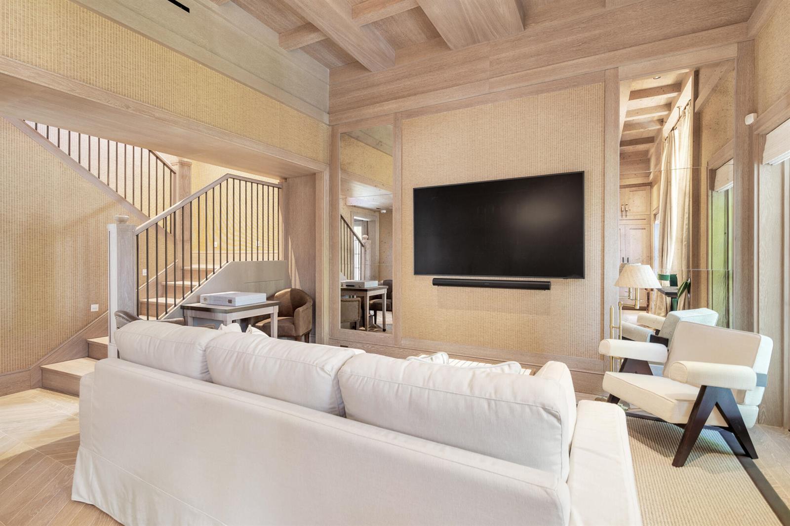 A living room features light wood paneling, a wall-mounted television, and a white sofa — 236 Phipps Plaza # 201, Palm Beach FL 33480, PALM BEACH, FL
