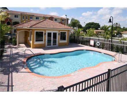 A swimming pool with a surrounding patio and a small clubhouse building in the background — 141 NW 2nd Ave # 7, Hallandale Beach FL 33009, HALLANDALE BEACH, FL