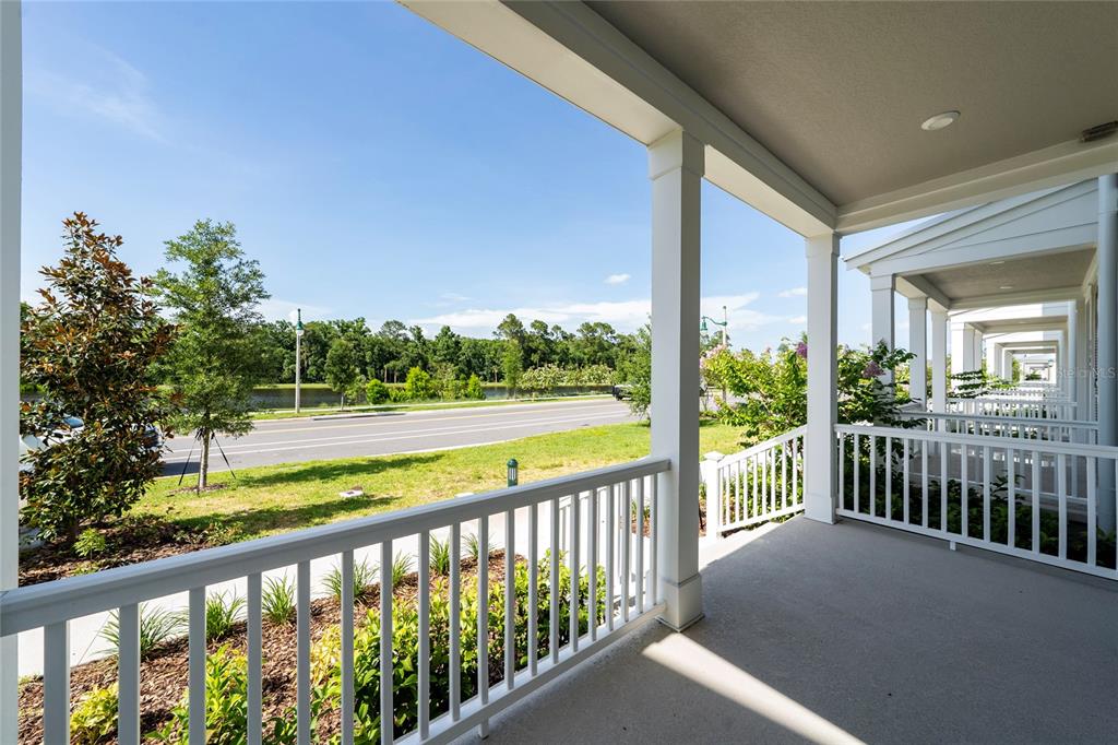 A covered porch with white railings overlooks a road, green space, and a line of trees — 2402 CELEBRATION BOULEVARD, KISSIMMEE, FL