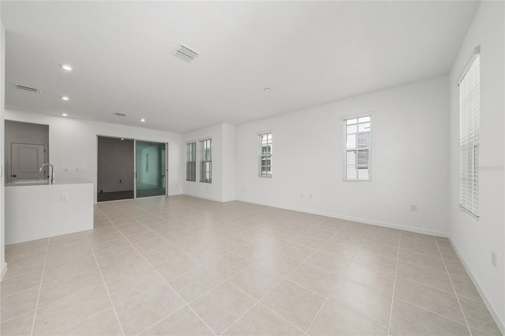 A bright, open-concept living area features white walls, tile flooring, and multiple windows — 2402 CELEBRATION BOULEVARD, KISSIMMEE, FL