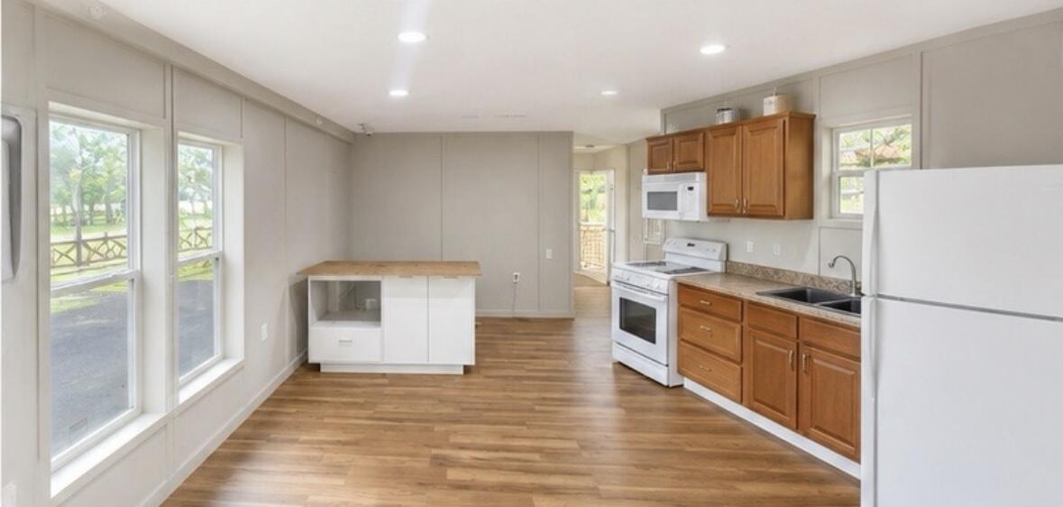 A kitchen with wood cabinets, white appliances, a small island, and light gray walls — 875 N Cabbage Palm Street, Clewiston FL 33440, CLEWISTON, FL