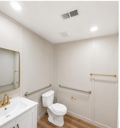 A bathroom features a white vanity, a toilet with grab bars, and light-colored wall paneling — 875 N Cabbage Palm Street, Clewiston FL 33440, CLEWISTON, FL
