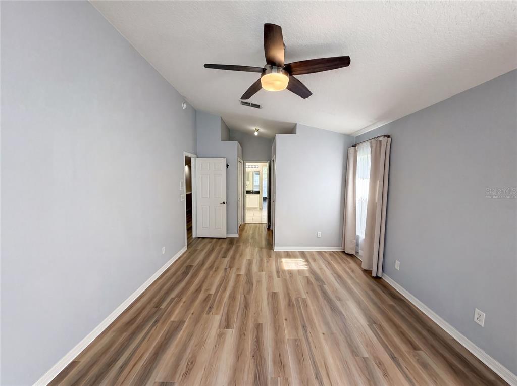 An empty room features light gray walls, wood-look flooring, and a ceiling fan — 1619 RIVER BIRCH AVENUE, OVIEDO, FL