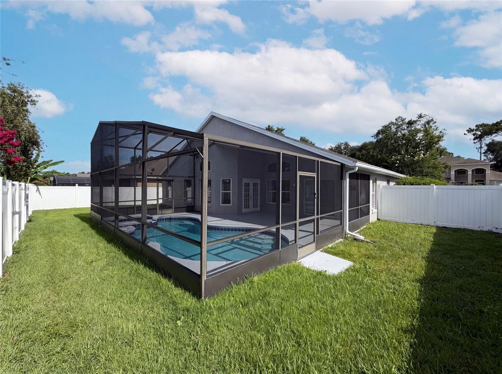 A backyard features a swimming pool enclosed by a screened lanai and white vinyl fencing — 1619 RIVER BIRCH AVENUE, OVIEDO, FL