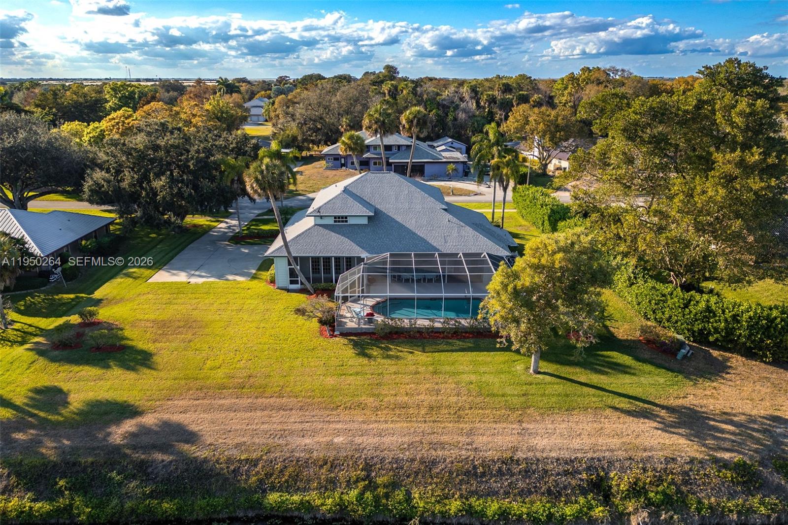 An aerial view shows a house with a screened pool and a large grassy yard — 108 Ridgewood Ave, Clewiston FL 33440, CLEWISTON, FL