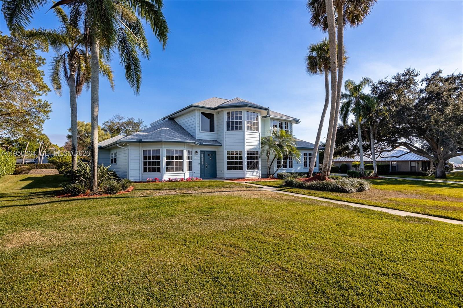 A two-story house with white siding and a blue front door sits on a lawn — 108 Ridgewood Ave, Clewiston FL 33440, CLEWISTON, FL
