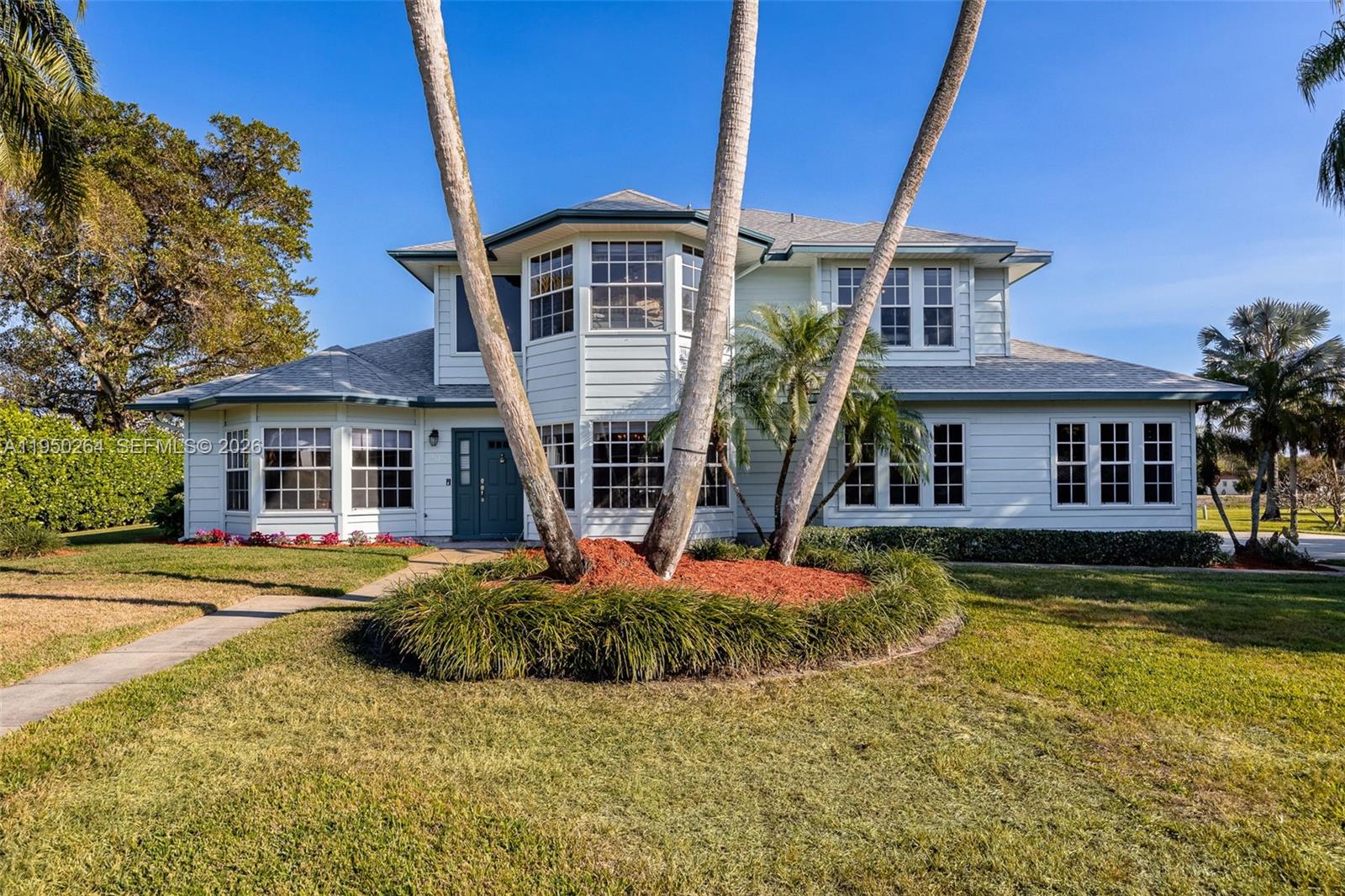 A two-story house with light-colored siding, a multi-paneled bay window, and tall palm trees — 108 Ridgewood Ave, Clewiston FL 33440, CLEWISTON, FL