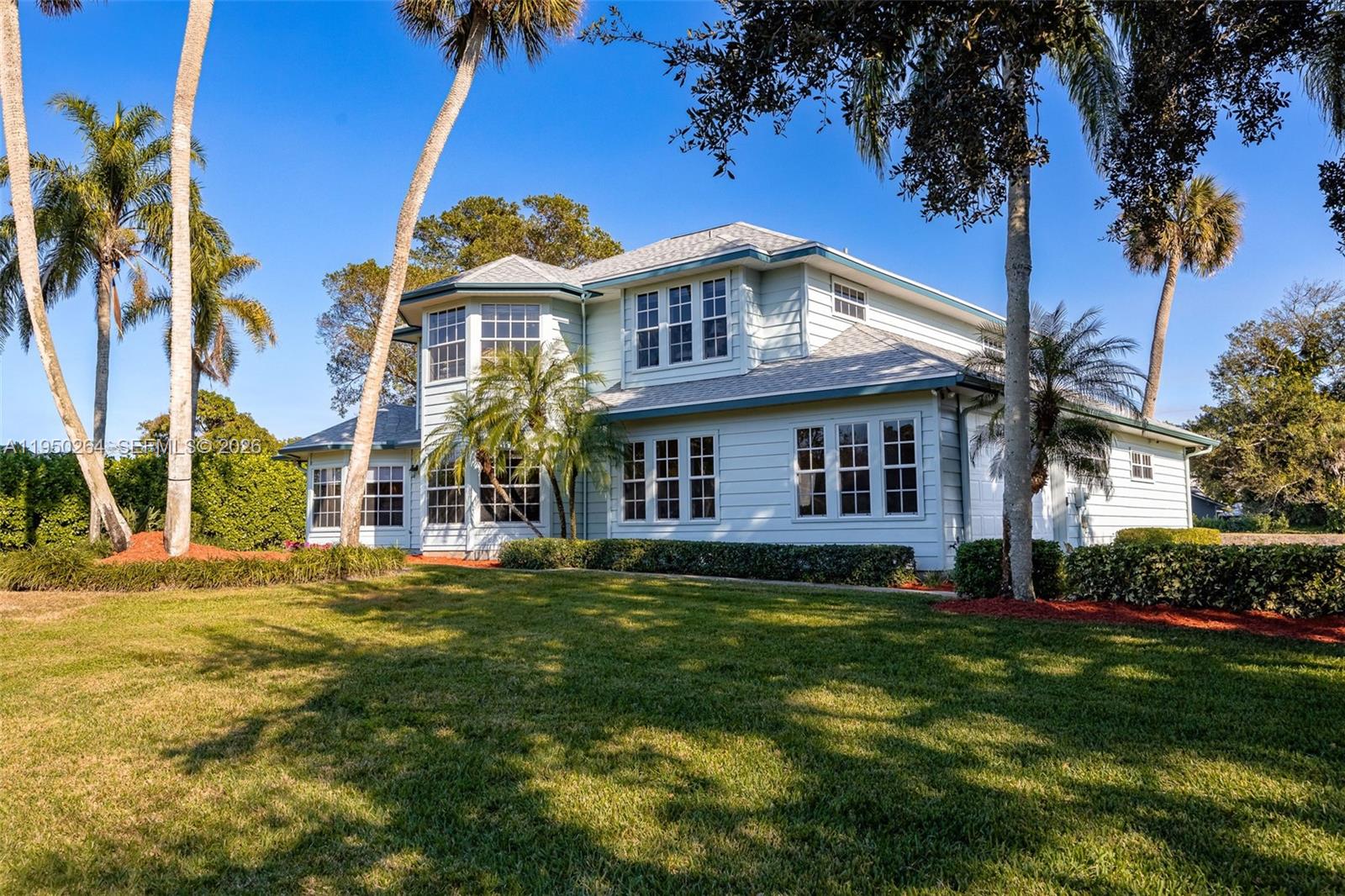 A two-story light blue house with a shingled roof stands on a grassy lawn — 108 Ridgewood Ave, Clewiston FL 33440, CLEWISTON, FL
