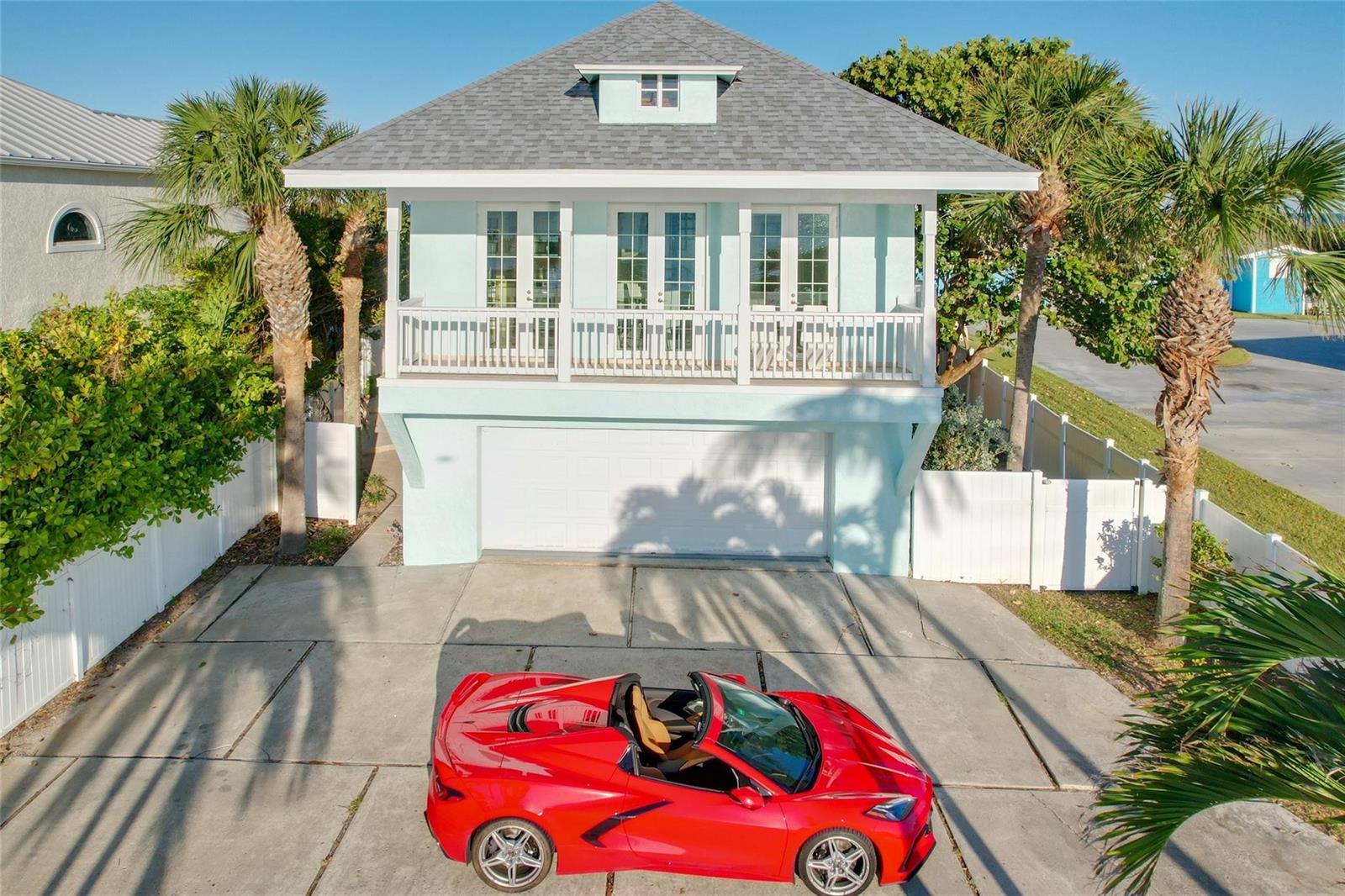 A red convertible sports car is parked in the driveway of a light blue house — 12880 Highway A1a, Vero Beach FL 32963, VERO BEACH, FL