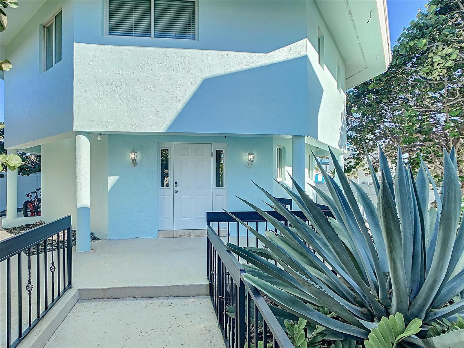 A light blue two-story house features a white front door and a metal railing walkway — 12880 Highway A1a, Vero Beach FL 32963, VERO BEACH, FL