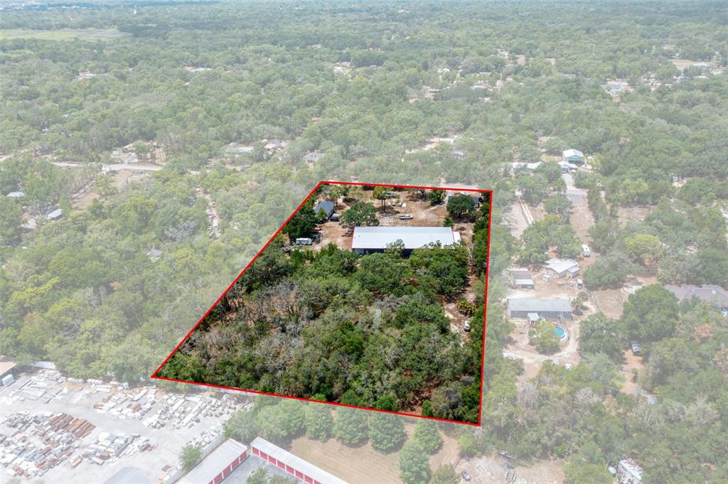 An aerial view shows a rectangular property outlined in red containing a large metal building — 12434 CHOCTAW TRAIL, HUDSON, FL
