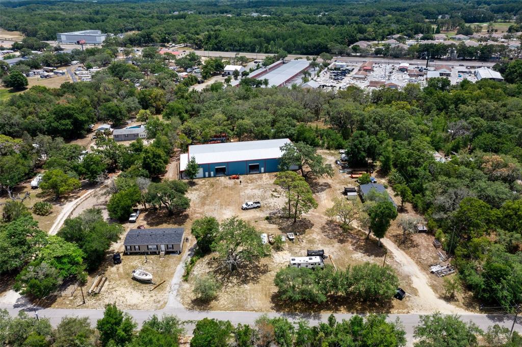 An aerial view shows a large metal warehouse, a house, and a trailer on a lot — 12434 CHOCTAW TRAIL, HUDSON, FL