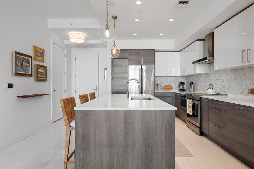 A modern kitchen features a central island, two-tone cabinetry, and stainless steel appliances — 111 S PINEAPPLE AVENUE UNIT 719, SARASOTA, FL