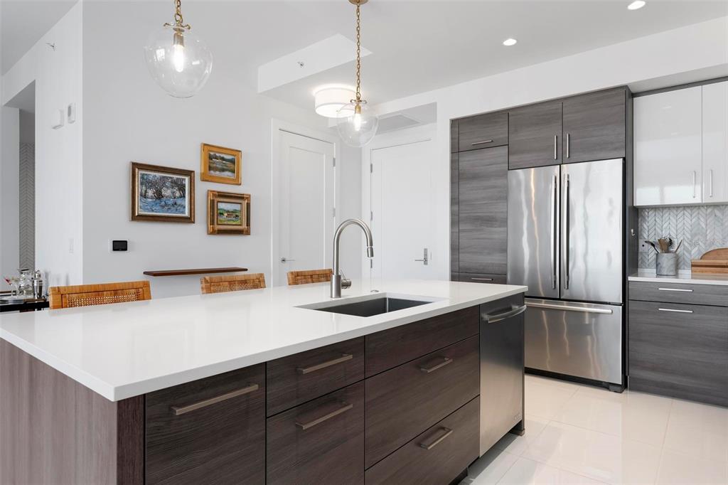 A modern kitchen features a dark wood island with a white countertop and stainless appliances — 111 S PINEAPPLE AVENUE UNIT 719, SARASOTA, FL
