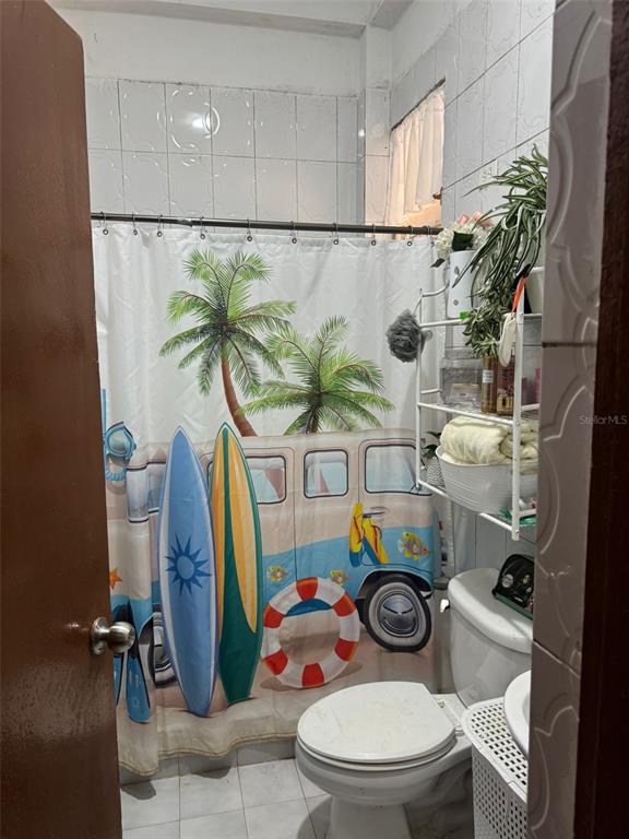 A blue house sits on a hillside next to a concrete driveway and flowering trees — calle 1 CALLE 1 UNIT A 10, TRUJILLO ALTO, PR