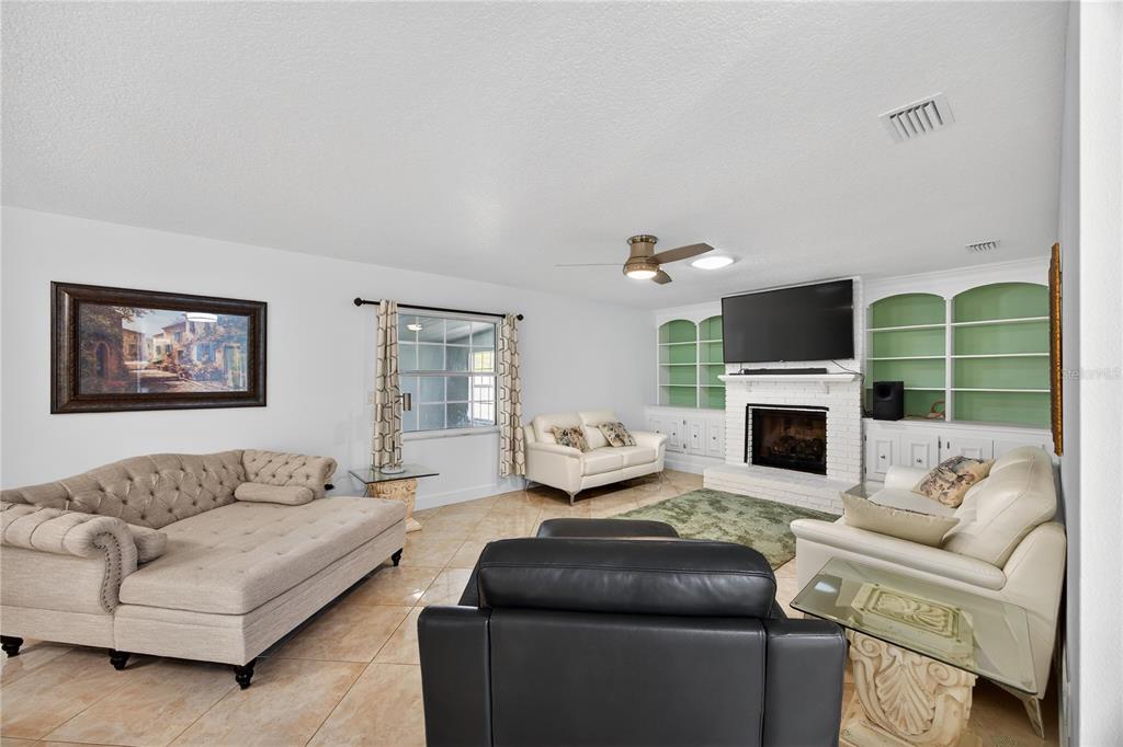 A living room features tile flooring, a brick fireplace with built-in shelves, and multiple sofas — 20 BLEAU COURT, PALM COAST, FL