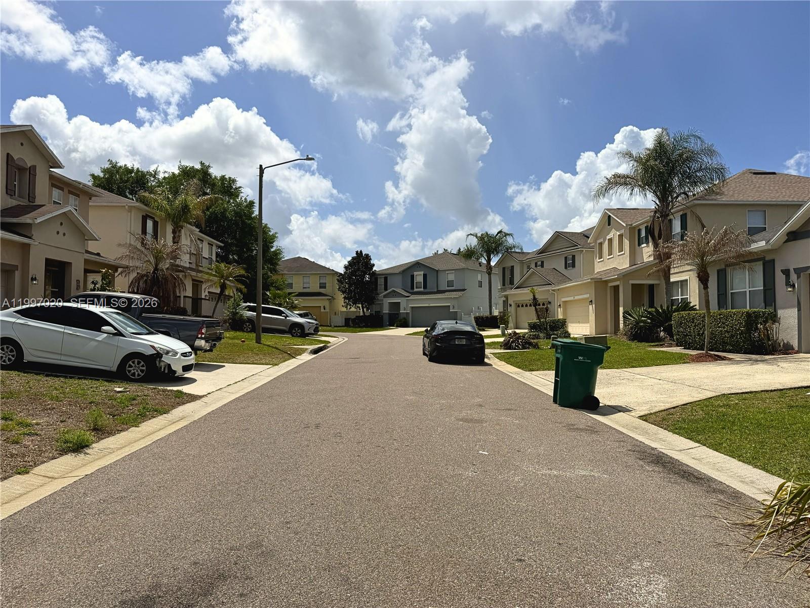 A residential street features two-story houses, parked vehicles, and a green trash bin — 233 Aldridge Ln, Davenport FL 33897, DAVENPORT, FL