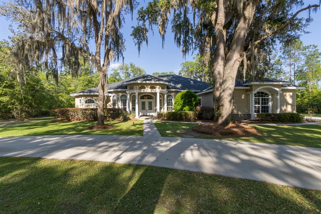 A single-story house with a columned entryway and Spanish moss hanging from large oak trees — 163 NW AMBER COURT, LAKE CITY, FL