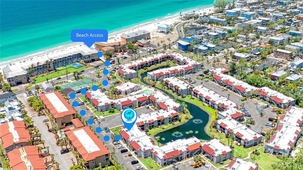 This aerial view shows a coastal condominium complex with a central pond and beach access — 1801 GULF DRIVE N UNIT 176, BRADENTON BEACH, FL
