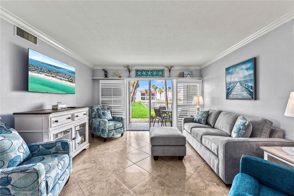 A living room features tile floors, a gray sofa, patterned armchairs, and sliding glass doors — 1801 GULF DRIVE N UNIT 176, BRADENTON BEACH, FL