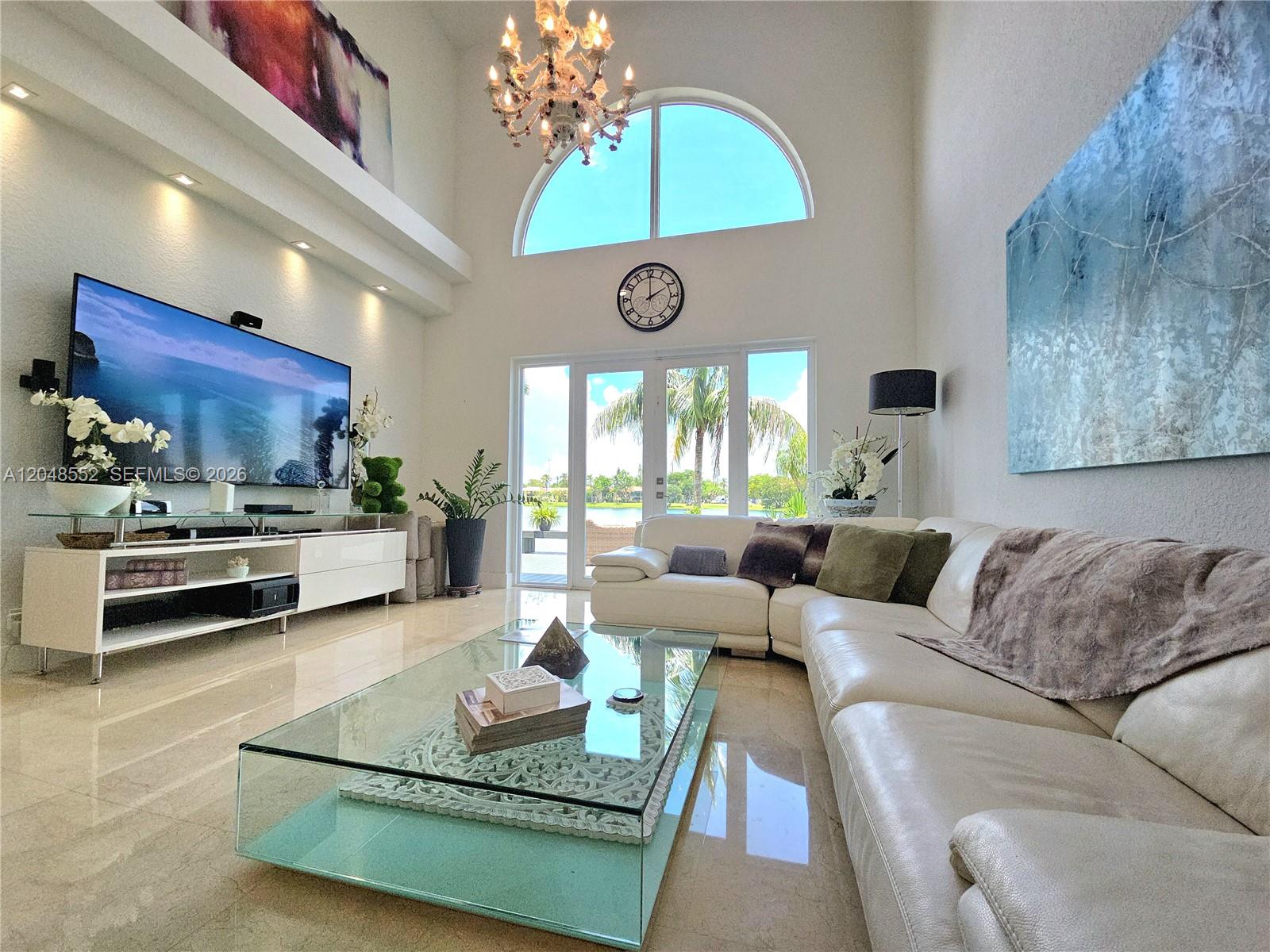 A bright living room features a large white sectional, glass coffee table, and vaulted ceilings — 783 NE 195th St # 0, Miami FL 33179, MIAMI, FL