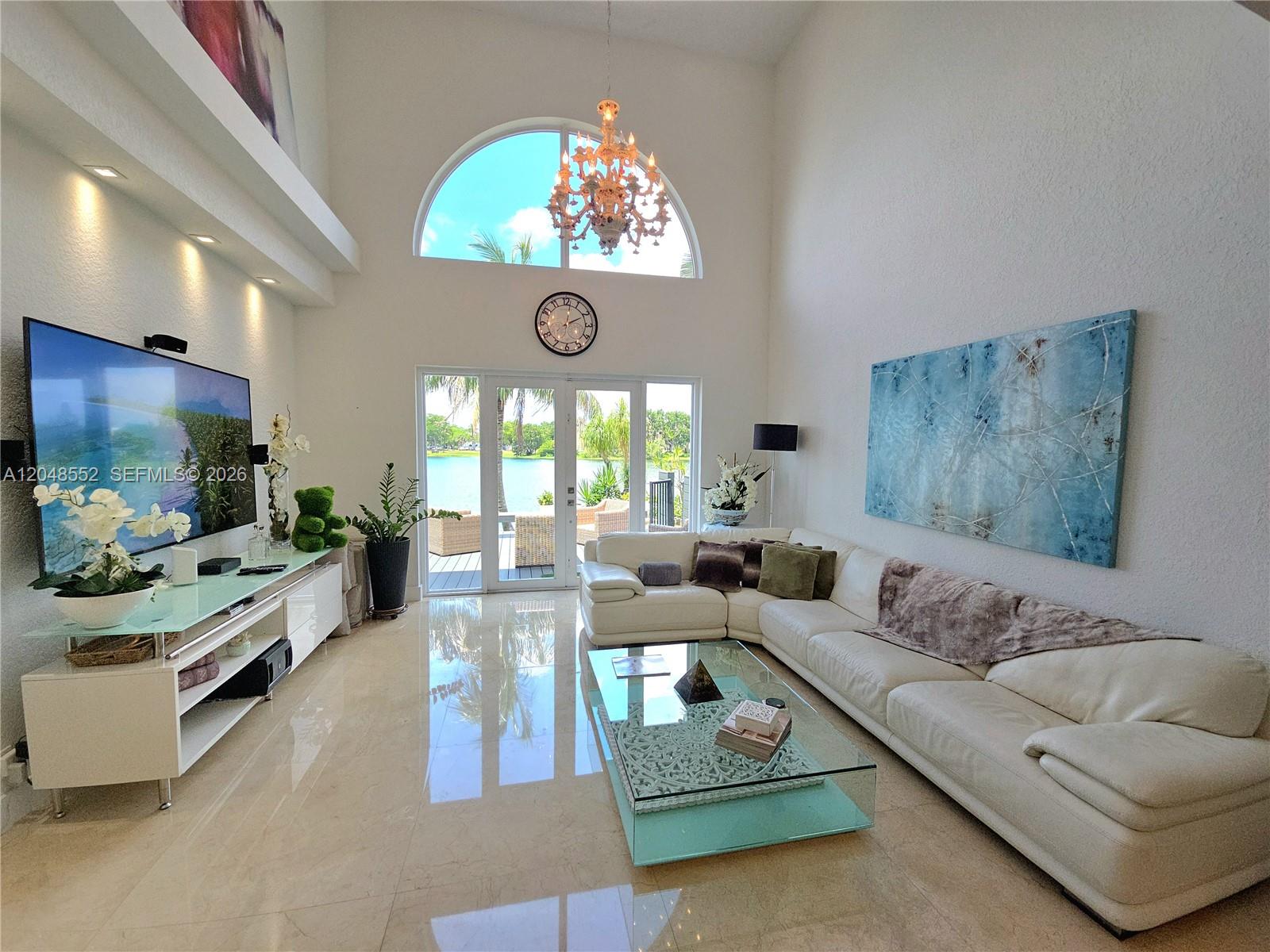 A bright living room features a white sectional sofa, glass coffee table, and vaulted ceilings — 783 NE 195th St # 0, Miami FL 33179, MIAMI, FL