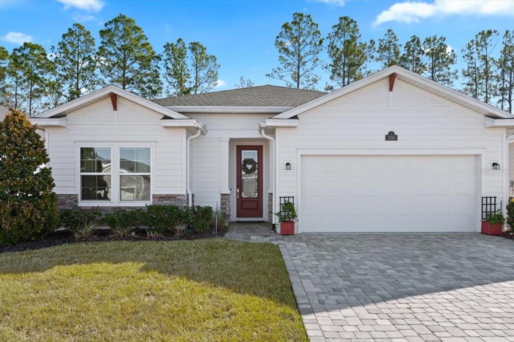 A single-story house with white horizontal siding, a stone base, and a paved driveway — 700 STILLWATER BOULEVARD, ST JOHNS, FL