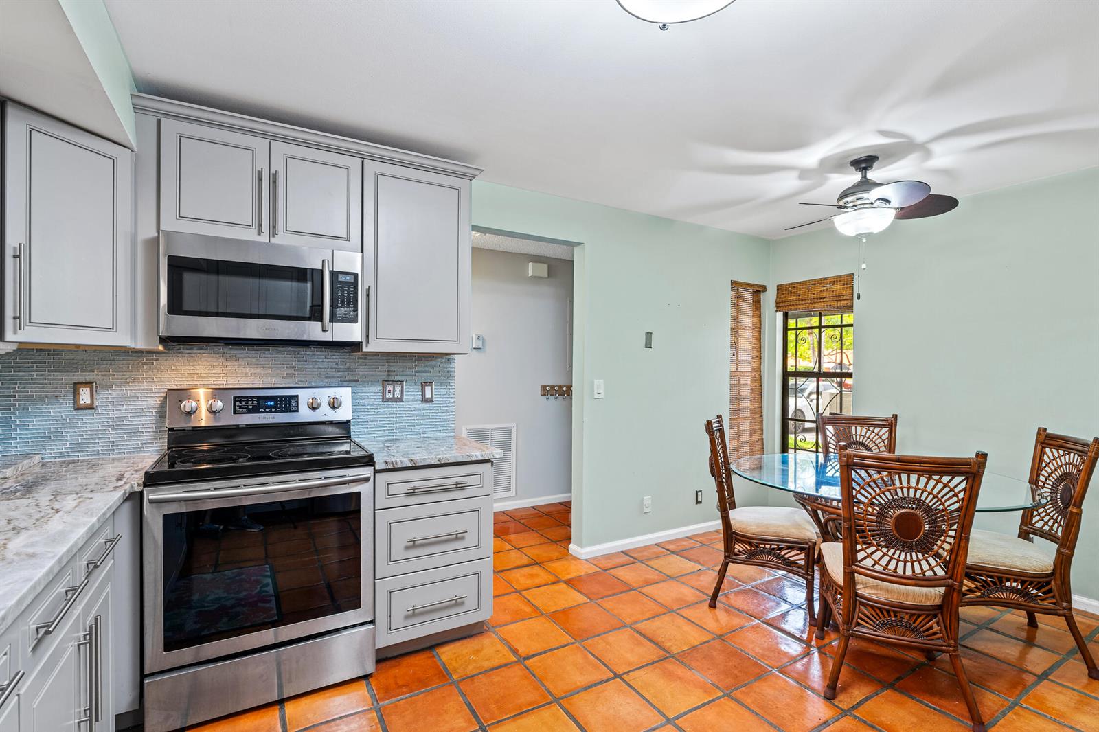 A kitchen with gray cabinets, stainless steel appliances, and a dining area with tile floors — 9728 Sills Drive E # 102, Boynton Beach FL 33437, BOYNTON BEACH, FL