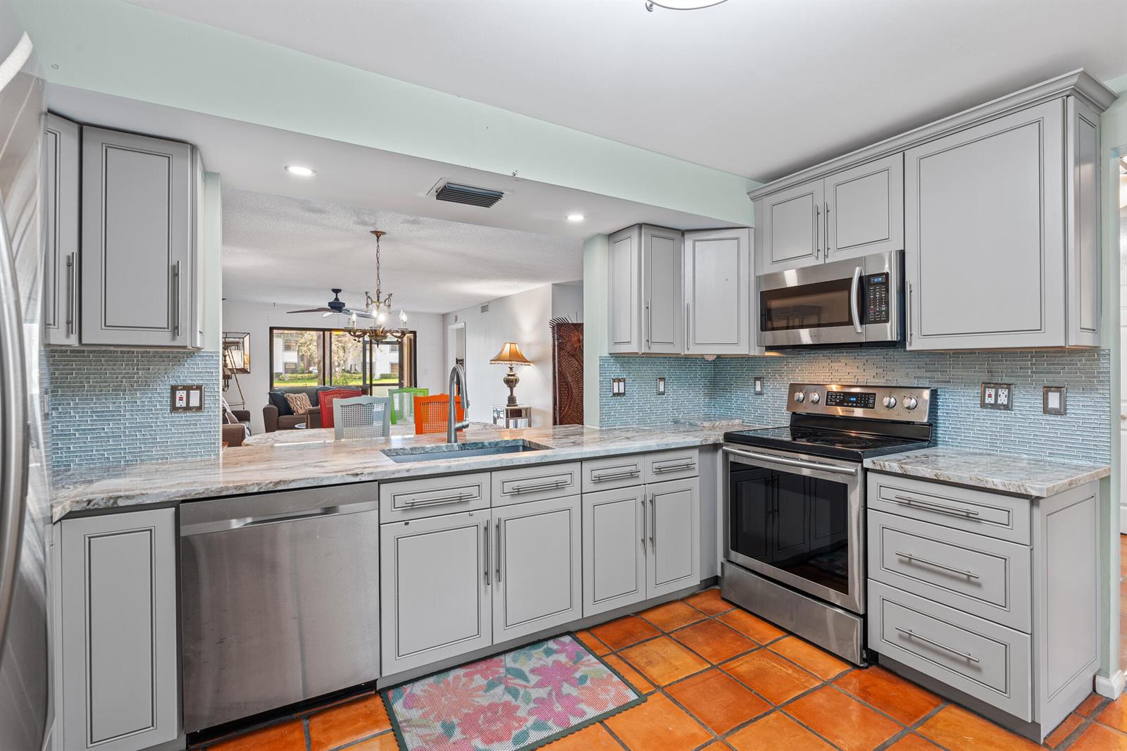 A kitchen with gray cabinets, stainless steel appliances, granite countertops, and terracotta tile flooring — 9728 Sills Drive E # 102, Boynton Beach FL 33437, BOYNTON BEACH, FL