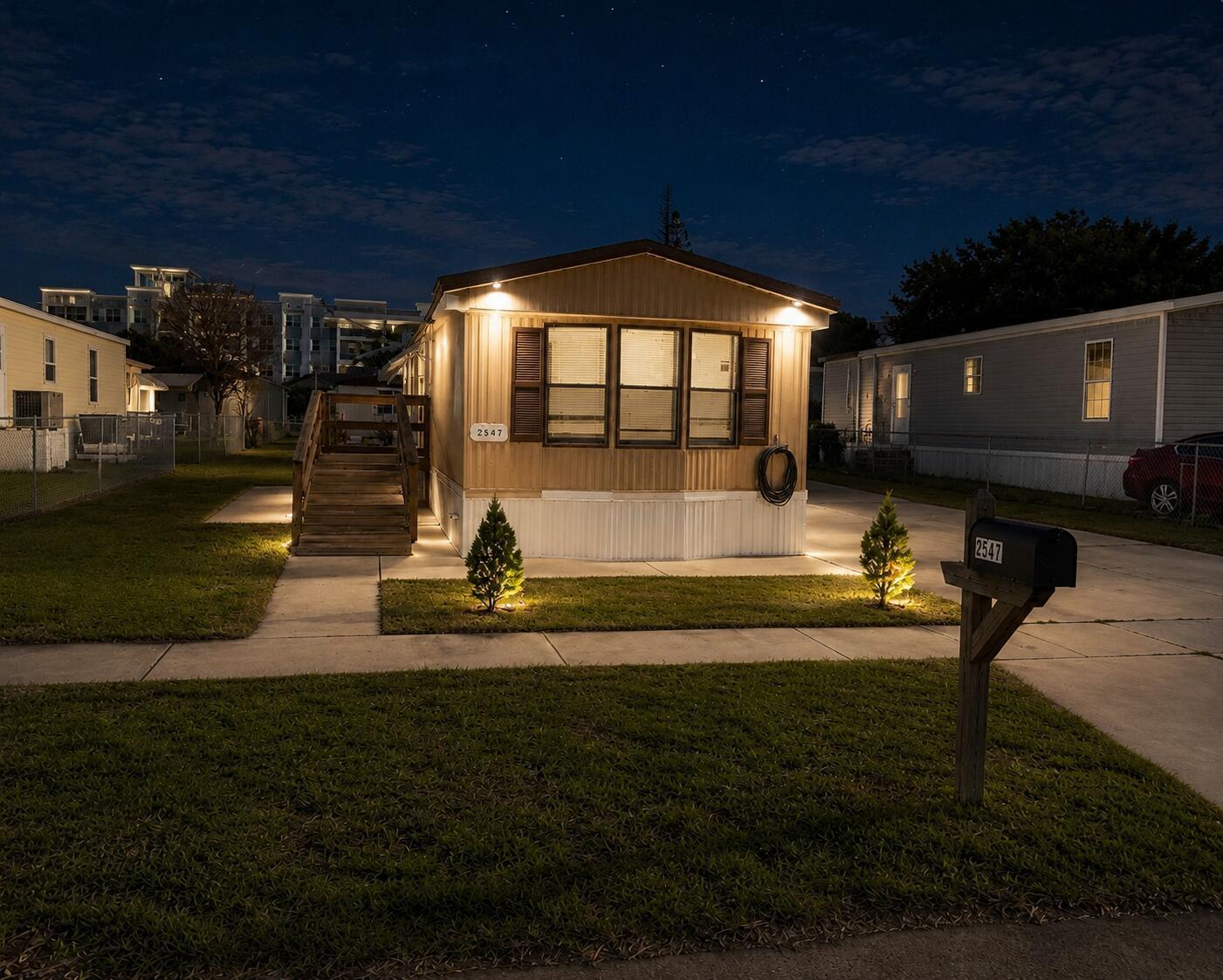 A single-story manufactured home at night with exterior lighting, a wooden staircase, and a mailbox — 2547 Chatham Way NE, Palm Bay FL 32905, PALM BAY, FL