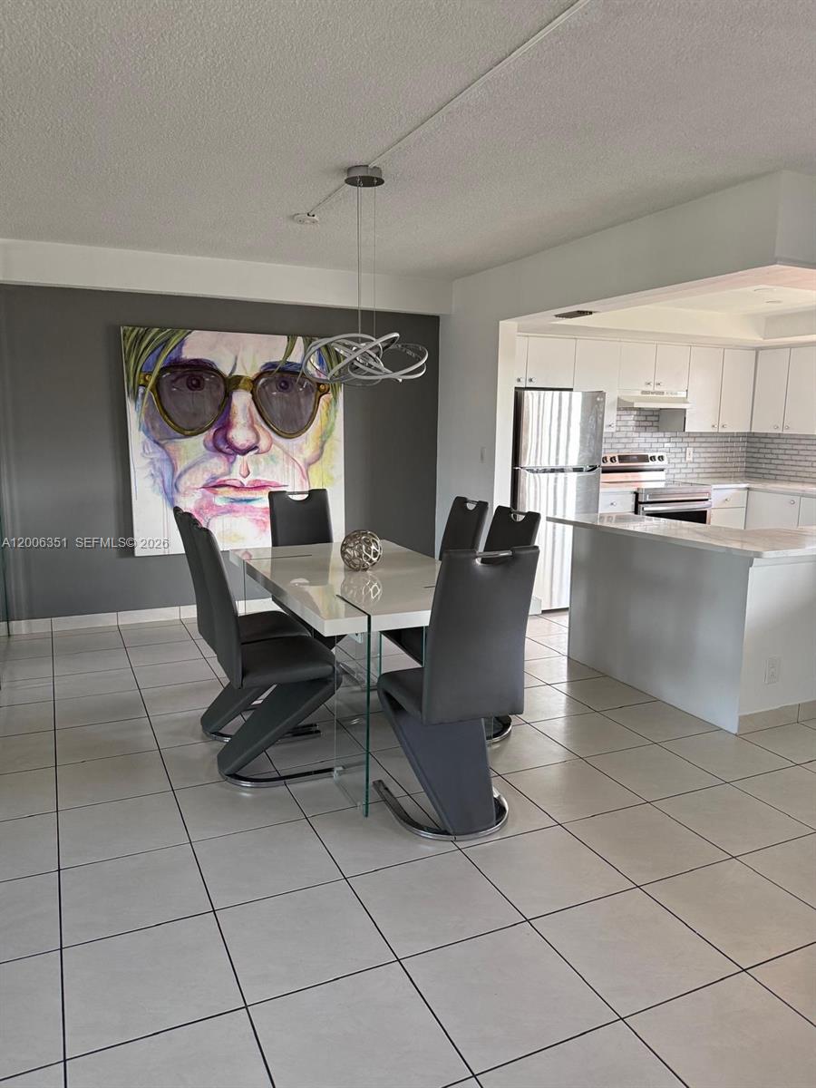 A dining area features a glass-topped table, gray chairs, and a large portrait painting — 200 NE 12th Ave # 7E, Hallandale Beach FL 33009, HALLANDALE BEACH, FL