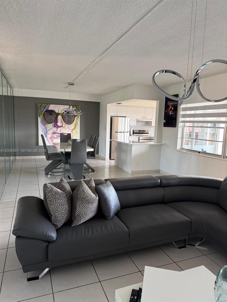 A living room with a gray sectional sofa, dining area, and open kitchen with white cabinets — 200 NE 12th Ave # 7E, Hallandale Beach FL 33009, HALLANDALE BEACH, FL