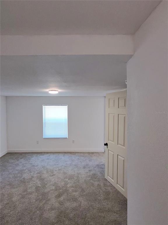 A room with gray carpet, white walls, a single window, and an open interior door — 411 W 7TH STREET, LAKELAND, FL