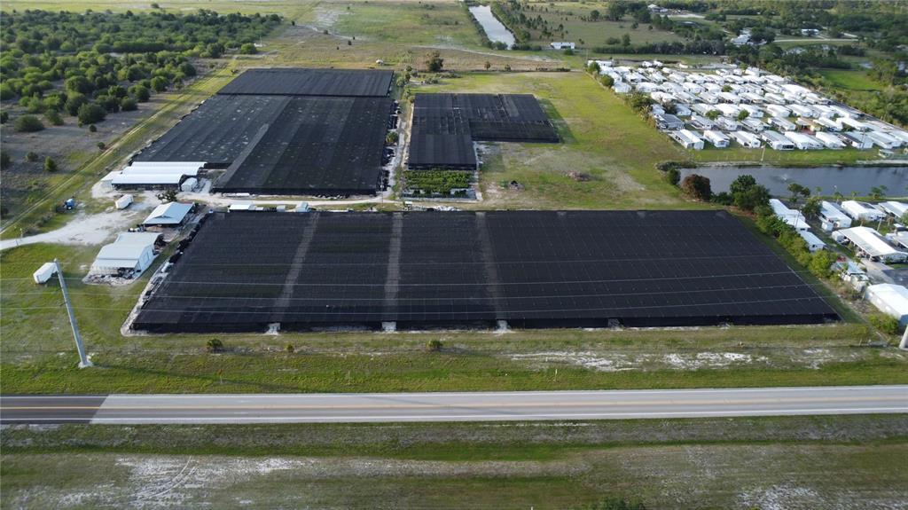 An aerial view shows a large agricultural nursery with shade structures next to a residential area — 300 STATE ROAD 70 E, LAKE PLACID, FL
