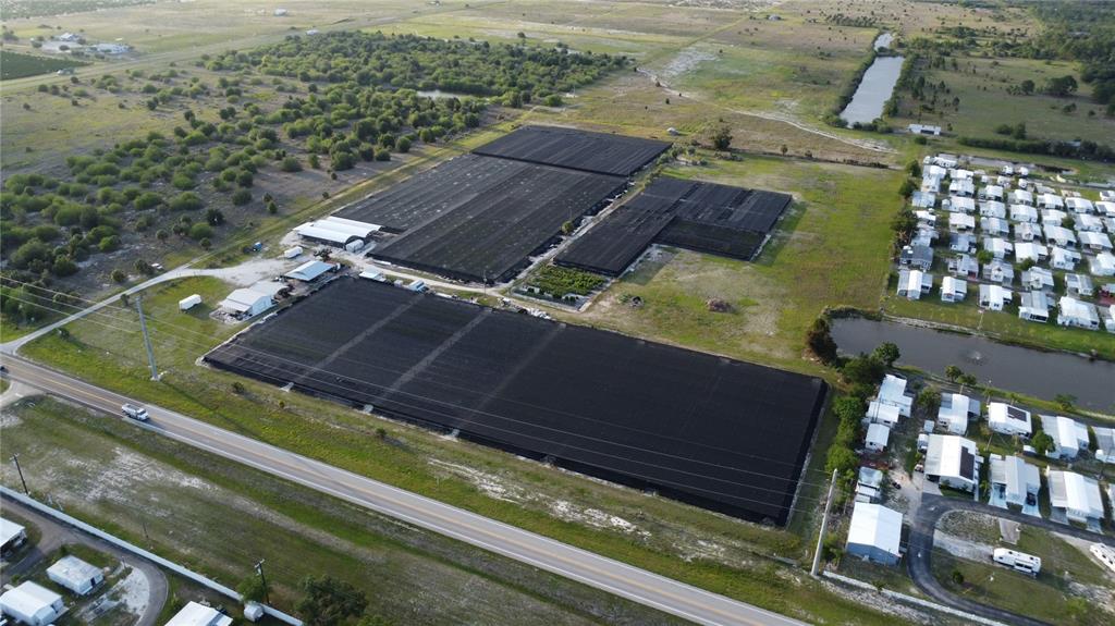 An aerial view shows a large agricultural nursery with black shade structures near a residential area — 300 STATE ROAD 70 E, LAKE PLACID, FL