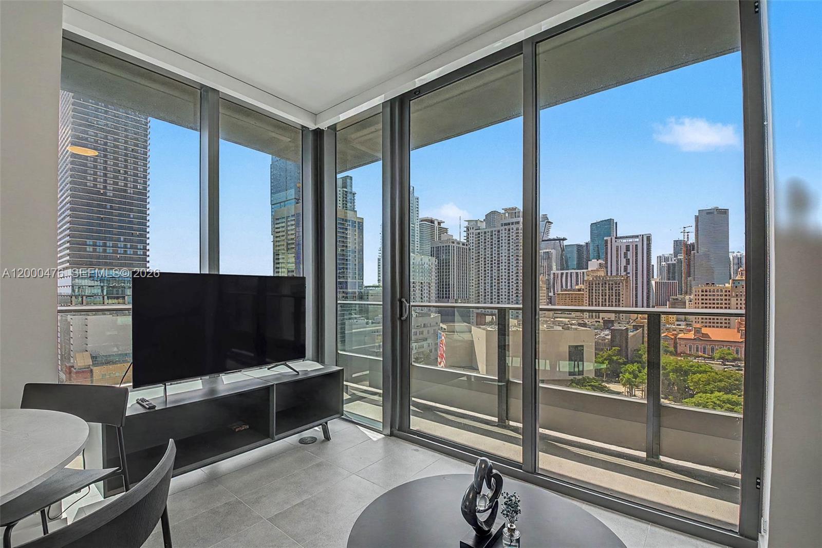 A living room features floor-to-ceiling windows with a view of a dense city skyline — 121 NE 5th ST # 1701, Miami FL 33132, MIAMI, FL