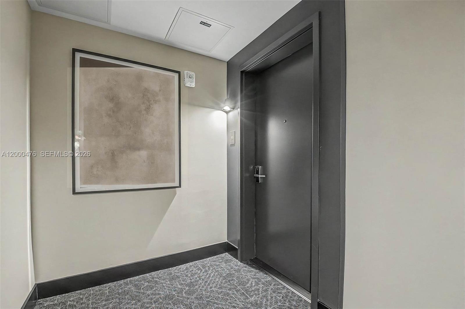 A dark gray door is set in a neutral-toned hallway with a framed abstract print — 121 NE 5th ST # 1701, Miami FL 33132, MIAMI, FL