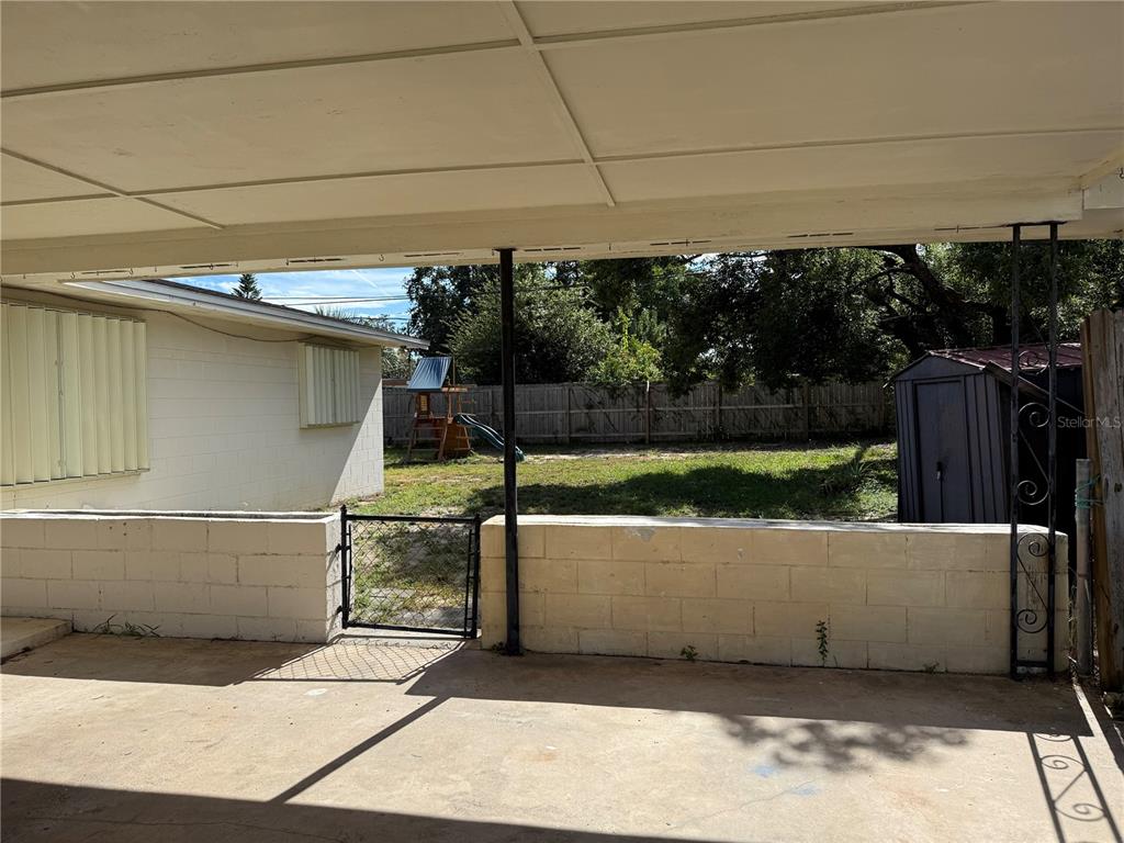 A covered concrete patio overlooks a fenced backyard with a small shed and play set — 845 EDGEWOOD ROAD, TITUSVILLE, FL