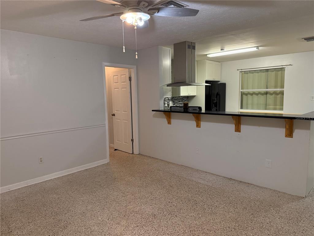 A living room with speckled flooring features a breakfast bar opening to a kitchen — 845 EDGEWOOD ROAD, TITUSVILLE, FL